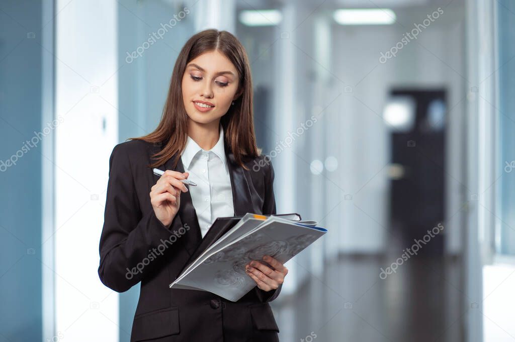 Portrait of young beautiful business woman in the office with documents in hand.