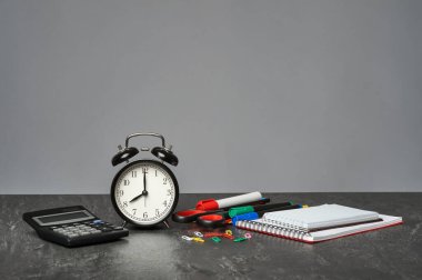 Ahşap masadaki kırtasiye malzemesi gri arka planda, yakın plan. Boşluğu kopyala.