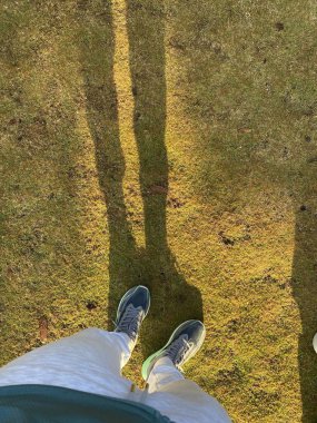 Yukarıdan çekilen bu resimde bir çift ayakkabı ve çimen tarlasının üzerine düşen bir gölge görülüyor. Işığın ve gölgenin etkileşimi ruhani bir kalite yaratır, dokuların altını çizer.