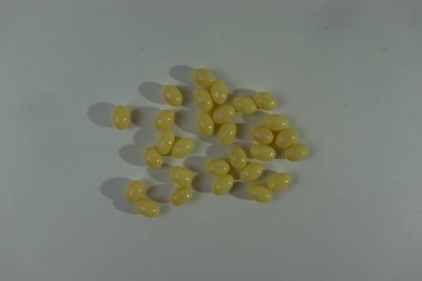 Küçük, sarı, fasulye şekilli şekerlerden oluşan bir koleksiyon temiz ve açık bir arkaplanda ustalıkla dağıtılmıştır. Bu resim, şeffaf bir arkaplan ile PNG biçiminde sunulmuştur, basit bir resmi vurgular