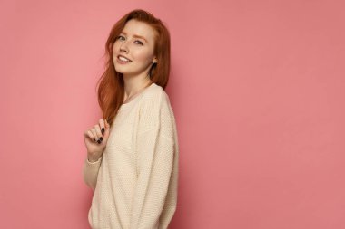 Redhead kız kameraya yan duruyor, saçlarına dokunur ve