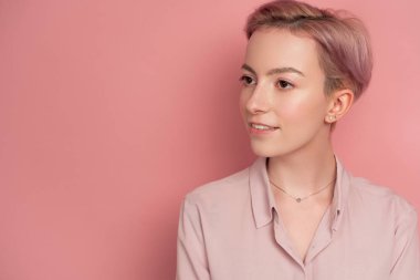 Pembe saçlı genç kadın sessiz bir gülümseme ile uzak bir yere bakar, p