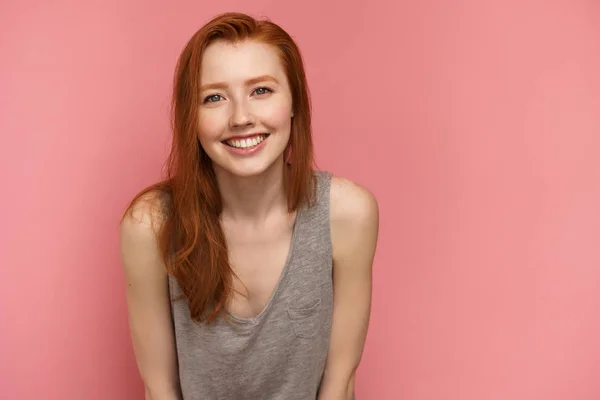 Menina ruiva sorri para a câmera se inclinando para a frente — Fotografia de Stock