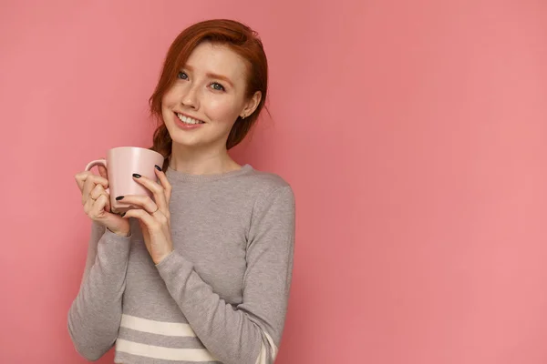 Redhead ung kvinna med en kopp leenden tittar på kamera — Stockfoto