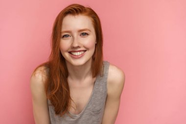 Redhead genç kadın kameraya gülümseyerek öne doğru eğilerek, yakın çekim