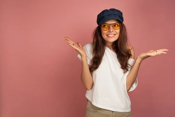 Jovem morena em uma camiseta branca joga as mãos como se ela diz oops, fundo rosa — Fotografia de Stock