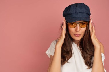 Genç esmer kameraya eğlenceli bakarak onu sarı güneş gözlüğü koyar