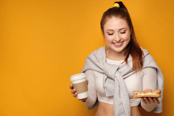 노란 배경 위에 음식을 들고 미소 포니 테일을 가진 젊은 여성 — 스톡 사진