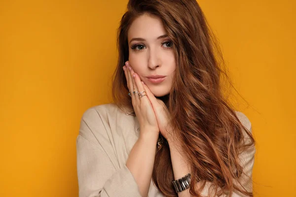 Retrato de uma menina ruiva pressionando a palma da mão na bochecha e olhando para a câmera . — Fotografia de Stock