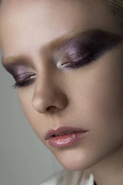 Nahporträt einer Platinblondine mit hellem Augen-Make-up in violetten Tönen mit metallischem Glanz. — Stockfoto