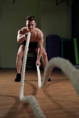 Atlet spor salonunda savaş ipi ile çalışıyor