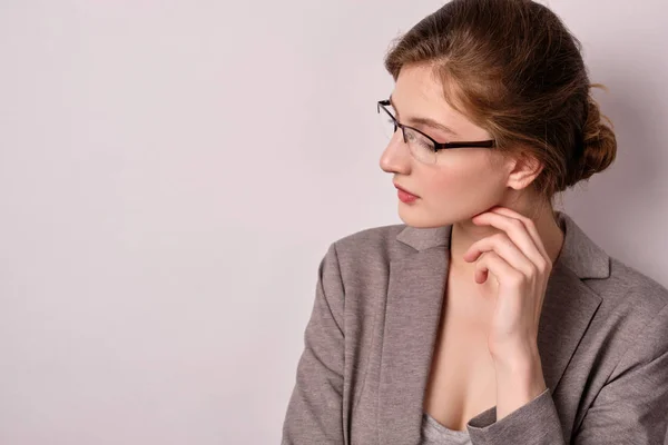 Retrato de cerca de una chica de pelo rubio con gafas y una chaqueta, girando la cabeza hacia un lado y cubriéndose los ojos — Foto de Stock