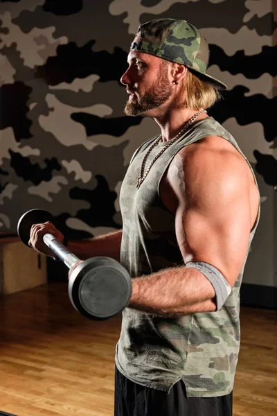 Hombre musculoso en una camiseta y una gorra de béisbol levanta la barra, marco vertical — Foto de Stock