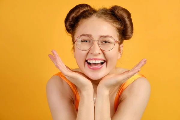 Nahes Porträt eines rothaarigen Mädchens mit runder Brille. Das Mädchen lacht fröhlich mit dem Kinn in der Handfläche. lizenzfreie Stockbilder