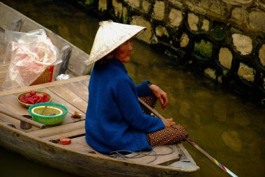 Vietnam old woman on the boat in river market