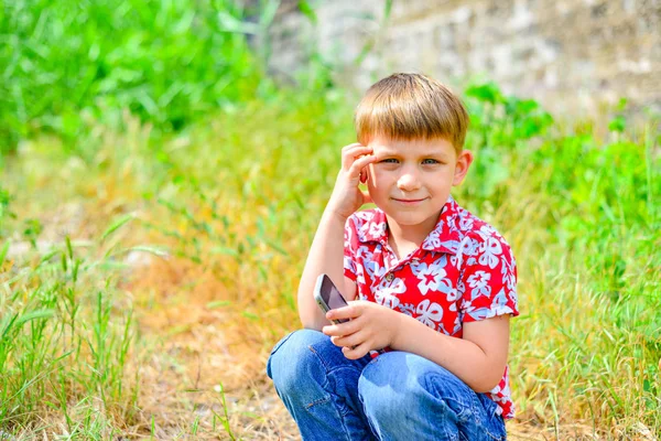 Szczęśliwe Dziecko Smartfonem Kuca Patrzy Kamerę — Zdjęcie stockowe