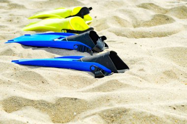 Dalış için sarı ve mavi kolların üst üste kum üzerinde yalan