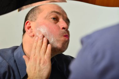 Bir yetişkin ve tıraşsız adam mavi gömlekli krem maske yüzünde, moda, stil ve kişisel bakım kavramı geçerlidir.