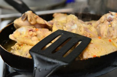 Aşçı tereyağı ve baharatlar ile bir tavada kızarmış tavuk karışımları.