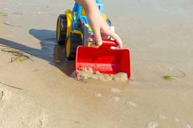 Denizde kum üzerinde çocuk oyuncak traktör