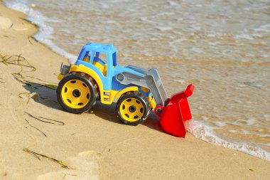 Denizde kum üzerinde çocuk oyuncak traktör