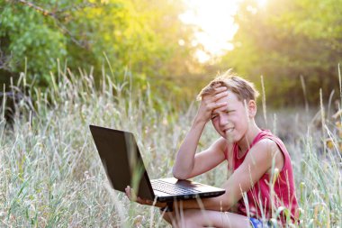 Ormanda bir takas bir dizüstü bilgisayar ile bir çocuk iş meşgul ve doğada açık havada oynamak