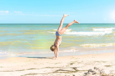 kız bir yaz güneşli bir gün deniz plajında elleriyle yürüyor.