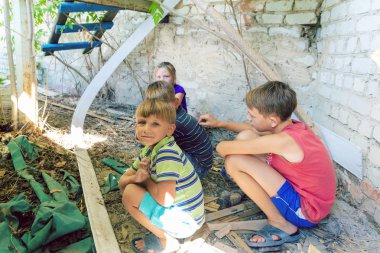 Sokak çocukları terkedilmiş bir evin köşesindeki çöplükte oturur. Aşamalı fotoğraf.