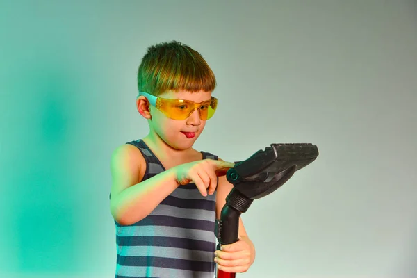 戴黄色护目镜的男孩在演播室里清洁吸尘器的刷子 — 图库照片