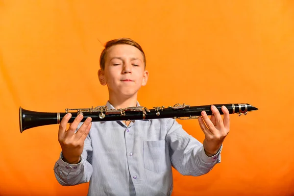 Menino Está Segurando Clarinete Preto Fundo Laranja — Fotografia de Stock