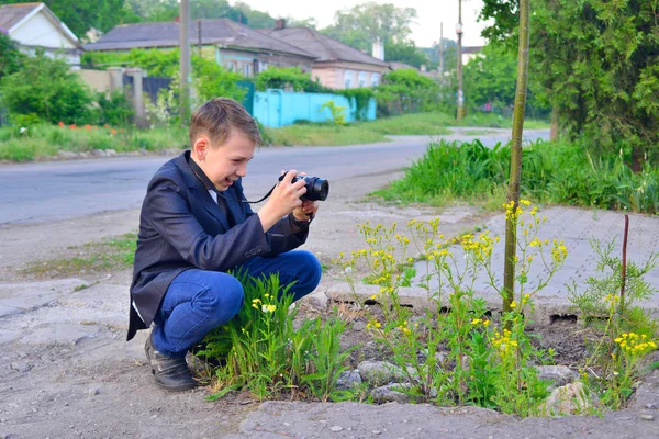 Chłopiec Kamerą Idzie Ulicą Robi Zdjęcia Dzikim Kwiatom — Zdjęcie stockowe