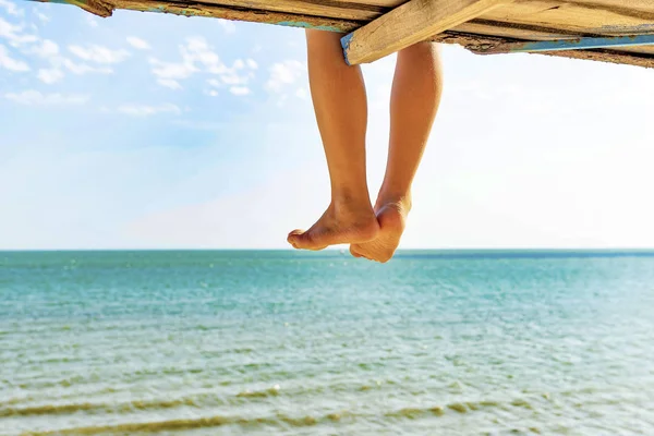 Feet hanging from the observation tower on the beach to the sea