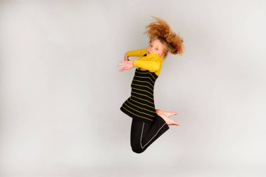 Spor kız farklı yönlerde gri bir arka planda atlar, bir atlama bir fotoğraf, saç yükselir