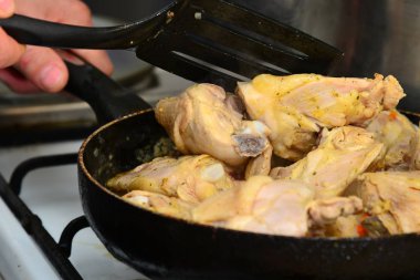 Aşçı tereyağı ve baharatlar ile bir tavada kızarmış tavuk karışımları.