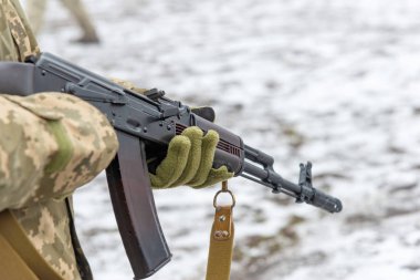 Bir Kalaşnikof saldırı tüfeği ile kamuflaj bir askeri asker bir sipariş bekliyor.