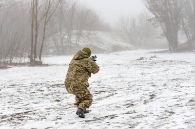 Bir silah ile kamuflaj bir askeri asker kış aylarında saldırı gider.