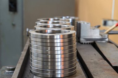 Yuvarlak demir ve düz halkalar işleme için makinede yatıyor.