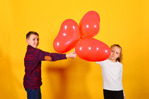 The guy gives the girl a bunch of red balloons in the shape of a heart, on a dark yellow background for Valentine's Day and March 8th.