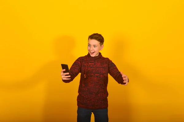 黄色背景上带智能手机的男孩 — 图库照片
