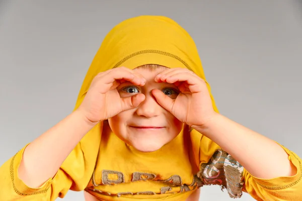 소년은 머리에 노란색 스웨터를 쌍안경을 보인다 — 스톡 사진