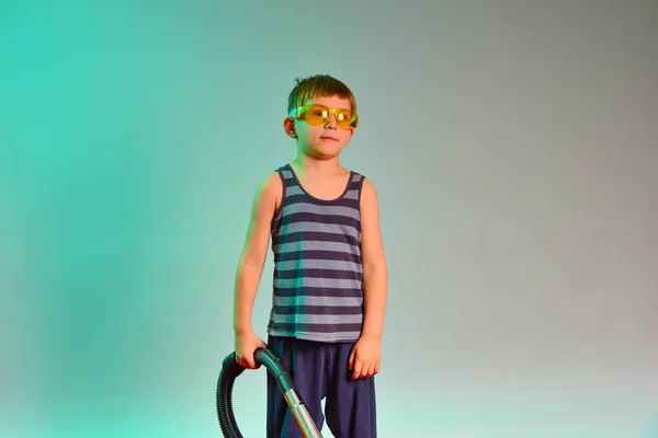 Boy in yellow goggles holding a vacuum cleaner handle