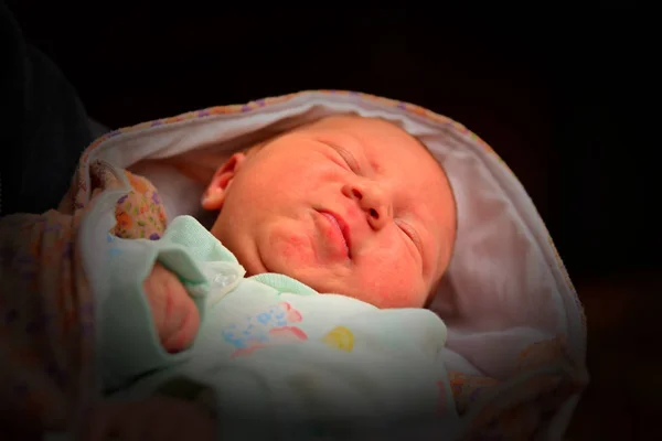 Happy and innocent newborn baby on a dark background.