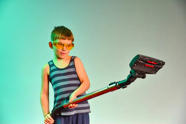 Boy in yellow goggles holding a vacuum cleaner handle