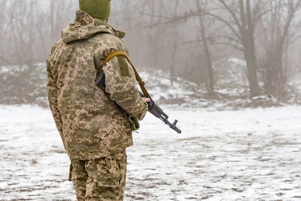 一名身穿迷彩服的军人手持卡拉什尼科夫冲锋枪正在等待命令 — 图库照片