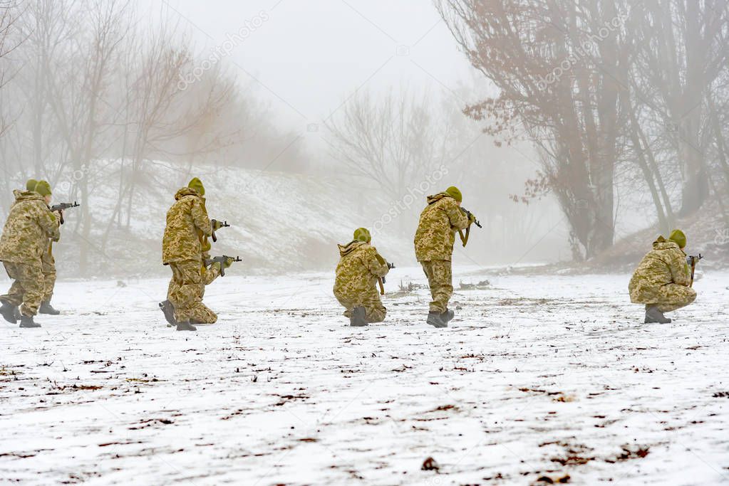 A combat squad in camouflage with a weapon goes on the offensive in winter.
