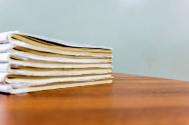 Bir kitap yığını kahverengi bir masada yatıyor, belgeler yakın-up yığılmış