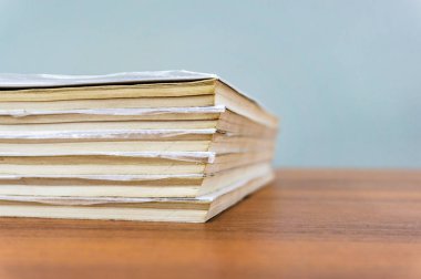 Bir kitap yığını kahverengi bir masada yatıyor, belgeler yakın-up yığılmış