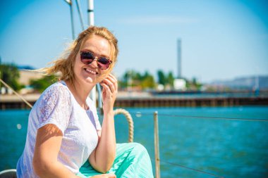 Etrafa bir yatın güvertesinde oturan bir kız