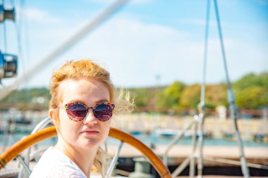 Bir kız bardaklarda etrafa bir yat güvertede tekerlek yanına oturur