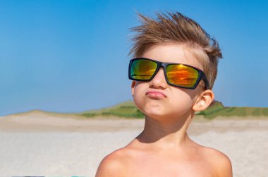 Sarı güneş gözlüklü bir çocuk baktı, kafasına saç geliştirir